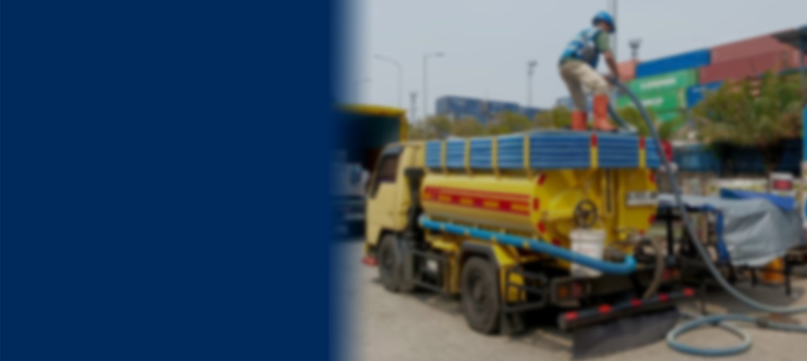 Petugas mengoperasikan truk sedot WC dan limbah cair menggunakan selang vakum besar di area industri Jabodetabek