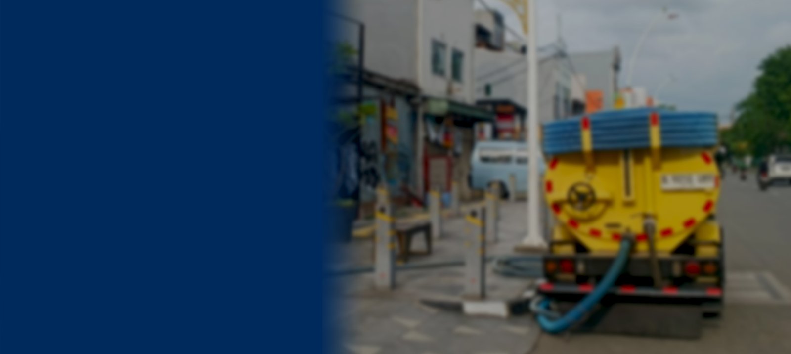 Truk sedot WC berwarna kuning sedang melayani penyedotan limbah di area perkotaan Jabodetabek dengan selang vakum biru
