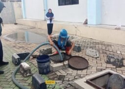 Petugas sedot WC melakukan penyedotan septic tank menggunakan selang vakum di area perkantoran