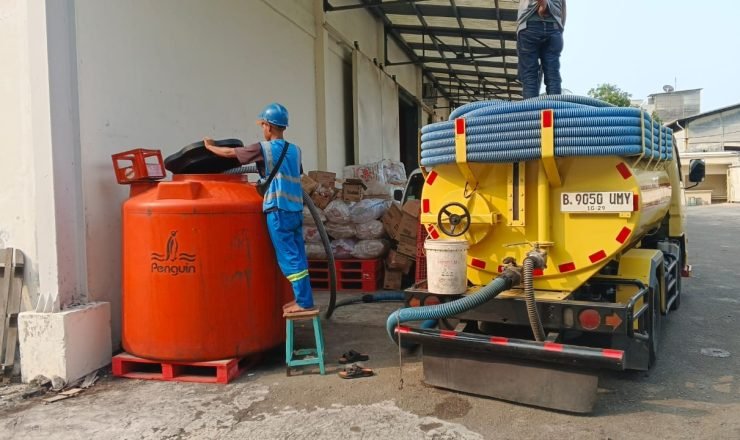 Petugas menyedot limbah cair menggunakan truk tinja ke tangki penampungan di area industri
