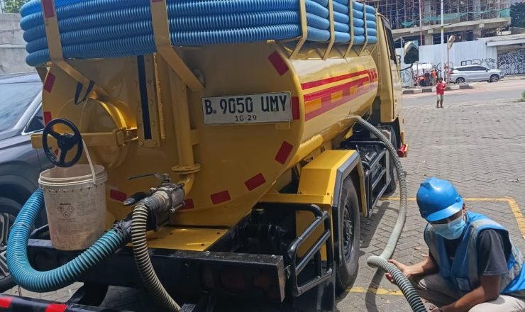 Proses sedot WC menggunakan truk tinja dan selang vakum oleh petugas profesional