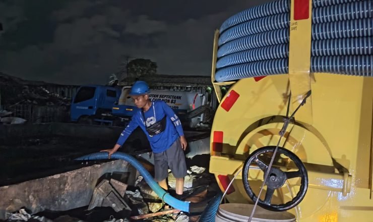 Petugas sedot WC menyedot limbah septic tank menggunakan truk tinja pada malam hari