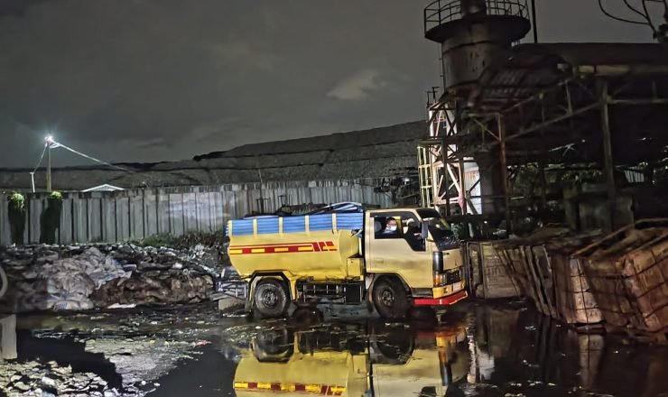 Truk pengangkut limbah cair beroperasi di area pengolahan limbah industri pada malam hari