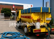 Truk tangki kuning Jasa Limbah terparkir di area belakang fasilitas industri siap mengangkut limbah
