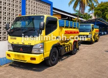 Truk sedot limbah JasaLimbah.com berwarna kuning dengan selang vakum di area operasional